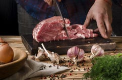 Butcher cutting pork on wooden board on a wooden table on the dark background stock images Butcher cutting pork on wooden board on a wooden table on the dark background stock images