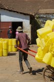 Man som drar rickshawen som laddas med plast- trummor royaltyfri fotografi Man som drar rickshawen som laddas med plast- trummor royaltyfri fotografi