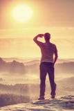Man is stand on edge and enjoying dramatic overlook of misty landscape stock photo Man is stand on edge and enjoying dramatic overlook of misty landscape stock photo