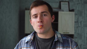 Man sucks lollipop and looks at the camera