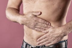 Man suffering from pain in his side. Pink background. Stomach pain, pancreas, kidneys royalty free stock photo Man suffering from pain in his side. Pink background. Stomach pain, pancreas, kidneys royalty free stock photo
