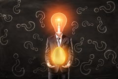 Man in suit with lightbulb instead head, levitating big shiny golden egg above palms, standing against black wall with royalty free stock photos Man in suit with lightbulb instead head, levitating big shiny golden egg above palms, standing against black wall with royalty free stock photos