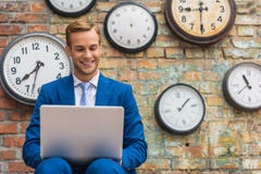 Man in suit sitting near wall with clocks royalty free stock photography Man in suit sitting near wall with clocks royalty free stock photography
