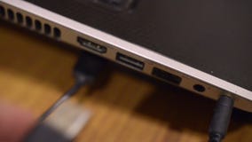 Man takes usb wire into the black notebook. Video closeup.