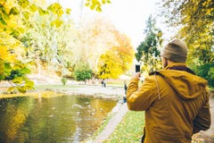 Man taking picture in city park on the lake. In autumn day Stock Photo Man taking picture in city park on the lake. In autumn day Stock Photo