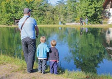 a man and two children fishing. Father and two sons fishing, trout at a trout farm. Children watch as fish.. stock images a man and two children fishing. Father and two sons fishing, trout at a trout farm. Children watch as fish.. stock images