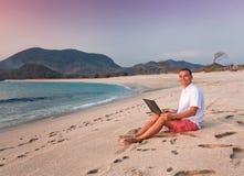 man-uses-laptop-remotely-beach-52589466.