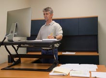 Man using stand up desk in office for good health Royalty Free Stock Images Man using stand up desk in office for good health Royalty Free Stock Images