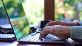 Man using touch screen laptop at desk in front of window, close up. stock photo Man using touch screen laptop at desk in front of window, close up. stock photo