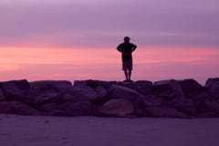 Man Watching a Pink and Violet Sunset at the Beach