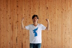 Man wearing Unification Korea flag color of shirt and standing with raised both fist on the wooden wall background royalty free stock image Man wearing Unification Korea flag color of shirt and standing with raised both fist on the wooden wall background royalty free stock image