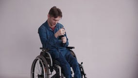 Man in wheelchair holding smartphone in his hands stock video footage Man in wheelchair holding smartphone in his hands stock video footage