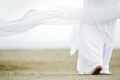Man in white walking on sand stock image Man in white walking on sand stock image