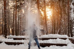 A man in the winter in the forest plays with snow, stands under a tree and shakes off the snow, covers it like an avalanche, from stock image A man in the winter in the forest plays with snow, stands under a tree and shakes off the snow, covers it like an avalanche, from stock image