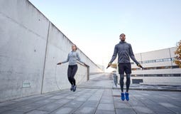 Man and woman exercising with jump-rope outdoors
