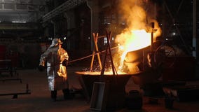 Man working with liquid metal in factory. Metal factory