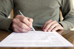 Man Writing on Paper with Pen on Table