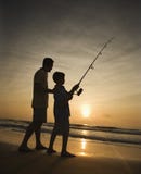 Man and young boy fishing in surf