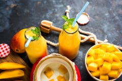Mango Lassi of smoothie in groot glas of kleine flessen met gestremde melk, de stukken van het besnoeiingsfruit en mixer stock afbeelding Mango Lassi of smoothie in groot glas of kleine flessen met gestremde melk, de stukken van het besnoeiingsfruit en mixer stock afbeelding