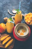 Mango Lassi of smoothie in groot glas of kleine flessen met gestremde melk, de stukken van het besnoeiingsfruit en mixer royalty-vrije stock fotografie Mango Lassi of smoothie in groot glas of kleine flessen met gestremde melk, de stukken van het besnoeiingsfruit en mixer royalty-vrije stock fotografie