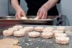Mani che creano, formarsi del cuoco unico, impanante la cotoletta del pollo con il coltello sulla cucina professionale del ristor immagine stock Mani che creano, formarsi del cuoco unico, impanante la cotoletta del pollo con il coltello sulla cucina professionale del ristor immagine stock