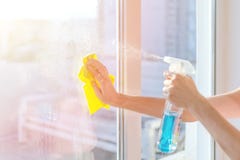 Mani con la finestra di pulizia del tovagliolo Lavare il vetro sulle finestre con spruzzo di pulizia immagini stock libere da diritti Mani con la finestra di pulizia del tovagliolo Lavare il vetro sulle finestre con spruzzo di pulizia immagini stock libere da diritti