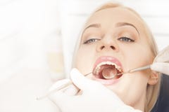 Mani del dentista che funzionano con i denti femminili immagine stock libera da diritti Mani del dentista che funzionano con i denti femminili immagine stock libera da diritti