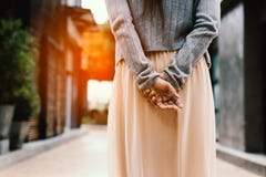 Mani della donna dietro lei indietro, esaminando qualcosa nella città immagine stock libera da diritti Mani della donna dietro lei indietro, esaminando qualcosa nella città immagine stock libera da diritti