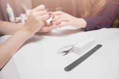 Manicure at beauty salon. Applying gel coating to girl with long hair. Close-up, warm lighting. Focus on tools royalty free stock image Manicure at beauty salon. Applying gel coating to girl with long hair. Close-up, warm lighting. Focus on tools royalty free stock image