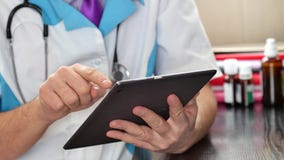 Manlig doktor som arbetar med en modern pekskärmminnestavladator arkivfoto Manlig doktor som arbetar med en modern pekskärmminnestavladator arkivfoto