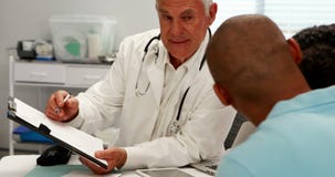 Manlig doktor som diskuterar den medicinska rapporten med patienten stock video Manlig doktor som diskuterar den medicinska rapporten med patienten stock video