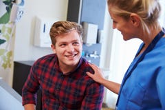 Manlig patient som uppmuntras av sjuksköterskan In Hospital Room arkivfoton Manlig patient som uppmuntras av sjuksköterskan In Hospital Room arkivfoton