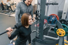 Manlig personlig konditioninstruktör som hjälper den unga kvinnan att göra genomkörare i idrottshall Sport, idrottsman nen, utbil royaltyfria foton Manlig personlig konditioninstruktör som hjälper den unga kvinnan att göra genomkörare i idrottshall Sport, idrottsman nen, utbil royaltyfria foton