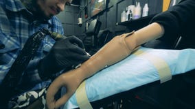 Manlig tattooer som arbetar på en bionisk hand i en mottagningsrum stock video Manlig tattooer som arbetar på en bionisk hand i en mottagningsrum stock video