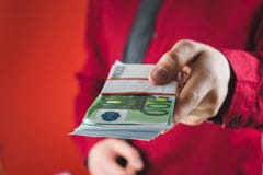 Mann in der roten Klage h?lt heraus ein Pack des Geldes in seiner Hand auf rotem Hintergrund lizenzfreie stockfotografie Mann in der roten Klage h?lt heraus ein Pack des Geldes in seiner Hand auf rotem Hintergrund lizenzfreie stockfotografie
