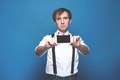 Mann im Hemd und in Hosenträger, die Smartphone mit leerem Bildschirm auf Blau stehen, halten und zeigen stockbilder Mann im Hemd und in Hosenträger, die Smartphone mit leerem Bildschirm auf Blau stehen, halten und zeigen stockbilder