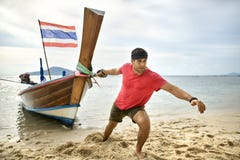 Mann mit Stoppel zieht hölzernes Boot durch Seil auf Sandstrand stockfotografie Mann mit Stoppel zieht hölzernes Boot durch Seil auf Sandstrand stockfotografie