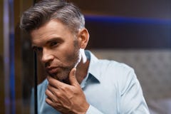 Mann-Pflegen Gut aussehender Mann mit Bart-rührendem Gesicht Zutreffen des transparenten Lacks lizenzfreie stockfotografie Mann-Pflegen Gut aussehender Mann mit Bart-rührendem Gesicht Zutreffen des transparenten Lacks lizenzfreie stockfotografie