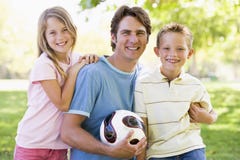 Mann und zwei junge Kinder, die Volleyball anhalten Mann und zwei junge Kinder, die Volleyball anhalten