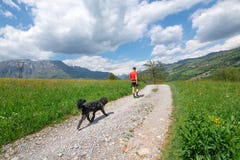 Mann während des Wegs in den Bergen mit seinem Hund, der ihm folgt lizenzfreie stockfotos Mann während des Wegs in den Bergen mit seinem Hund, der ihm folgt lizenzfreie stockfotos