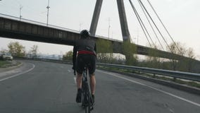 Mannelijke triathlete berijdende fiets als deel van zijn opleidingsprogramma Hij draagt zwarte uitrusting, helm en zonnebril Tria stock videobeelden Mannelijke triathlete berijdende fiets als deel van zijn opleidingsprogramma Hij draagt zwarte uitrusting, helm en zonnebril Tria stock videobeelden