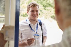 Mannelijke zorgarbeider die identiteitskaart tonen aan de hogere mens bij zijn voordeur stock afbeeldingen Mannelijke zorgarbeider die identiteitskaart tonen aan de hogere mens bij zijn voordeur stock afbeeldingen