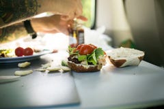 Mannen förbereder hamburgaren under campa skåpbiltur arkivbild Mannen förbereder hamburgaren under campa skåpbiltur arkivbild