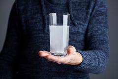 Mannen rymmer exponeringsglas av vatten med det upplösta pillret royaltyfri foto Mannen rymmer exponeringsglas av vatten med det upplösta pillret royaltyfri foto