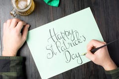 Mannen räcker att skriva ett lyckligt St Patrick dagkort royaltyfri fotografi Mannen räcker att skriva ett lyckligt St Patrick dagkort royaltyfri fotografi