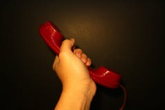 Mano ascendente cercana del vintage que sostiene el receptor de teléfono rojo fotografía de archivo libre de regalías Mano ascendente cercana del vintage que sostiene el receptor de teléfono rojo fotografía de archivo libre de regalías