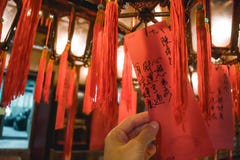 Mano che tiene una carta con le preghiere che pendono da una lanterna nell'uomo Mo Temple in Hong Kong immagini stock libere da diritti Mano che tiene una carta con le preghiere che pendono da una lanterna nell'uomo Mo Temple in Hong Kong immagini stock libere da diritti