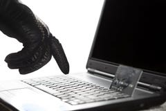 Mano con guantes de los piratas informáticos en el trabajo sobre un ordenador portátil imagenes de archivo Mano con guantes de los piratas informáticos en el trabajo sobre un ordenador portátil imagenes de archivo