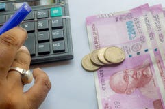Mano cosechada de una cuenta corriente de la mujer con la calculadora y sostener una pluma Los billetes y las monedas indios de l foto de archivo Mano cosechada de una cuenta corriente de la mujer con la calculadora y sostener una pluma Los billetes y las monedas indios de l foto de archivo