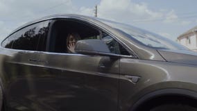 Mano d'ondeggiamento della ragazza alla macchina fotografica durante l'automobile che guida indietro video d archivio Mano d'ondeggiamento della ragazza alla macchina fotografica durante l'automobile che guida indietro video d archivio
